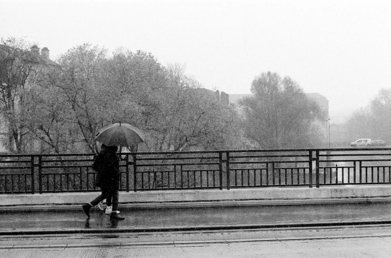 a person with an umbrella walking across a bridge