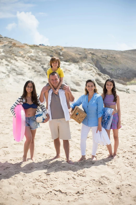 a young couple and their two daughters pose for a po on the beach