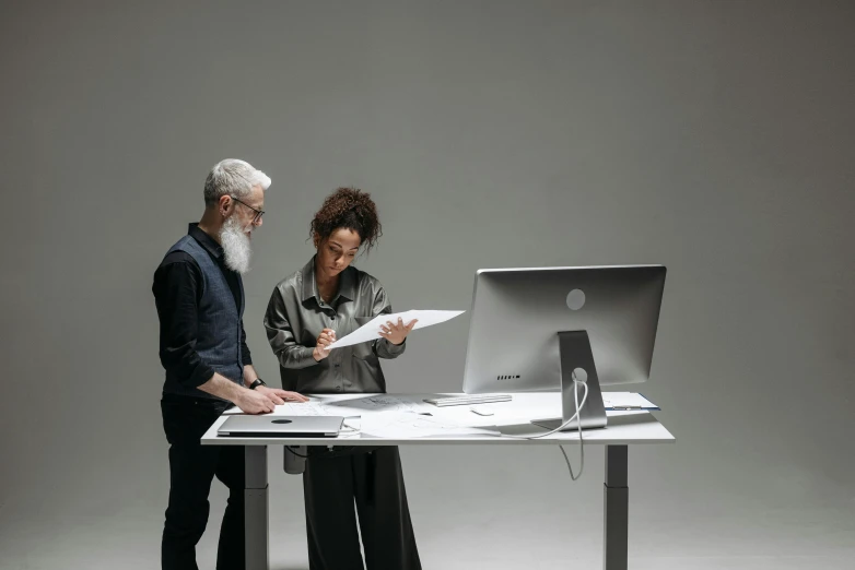 two people are standing next to a computer monitor