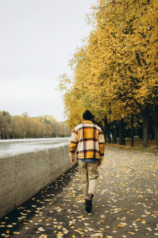 a man is walking on the sidewalk next to a tree