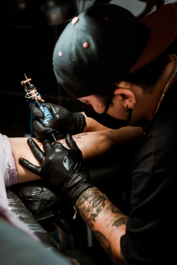 two men with gloves and tattoos working on another mans leg