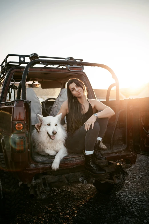 a woman and a dog sitting in the back of a truck