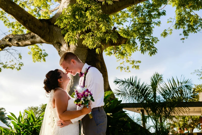 a man and a woman that are standing under a tree