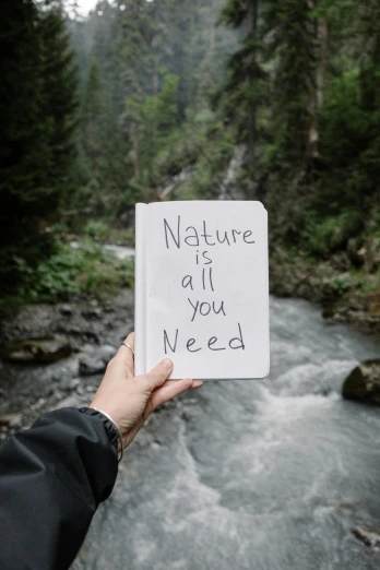 a person is holding a card that says nature is all you need