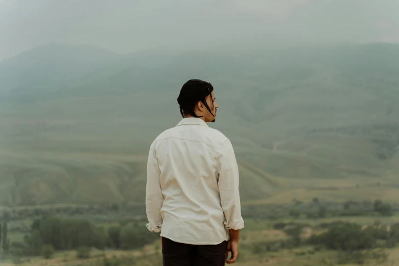 the man is looking at the mountains in the distance