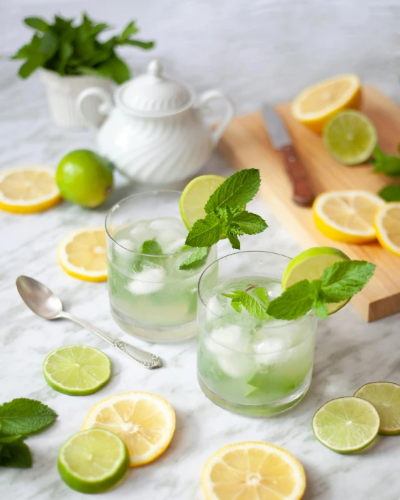 two glasses filled with water with limes and mint