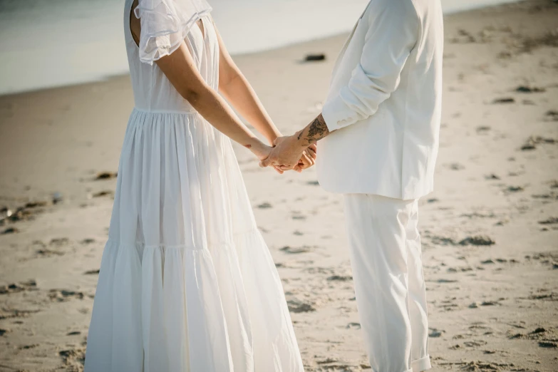 a newly married couple holding hands and standing together on the beach