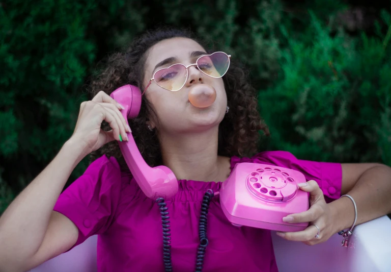 a woman in a pink dress using an old pink phone