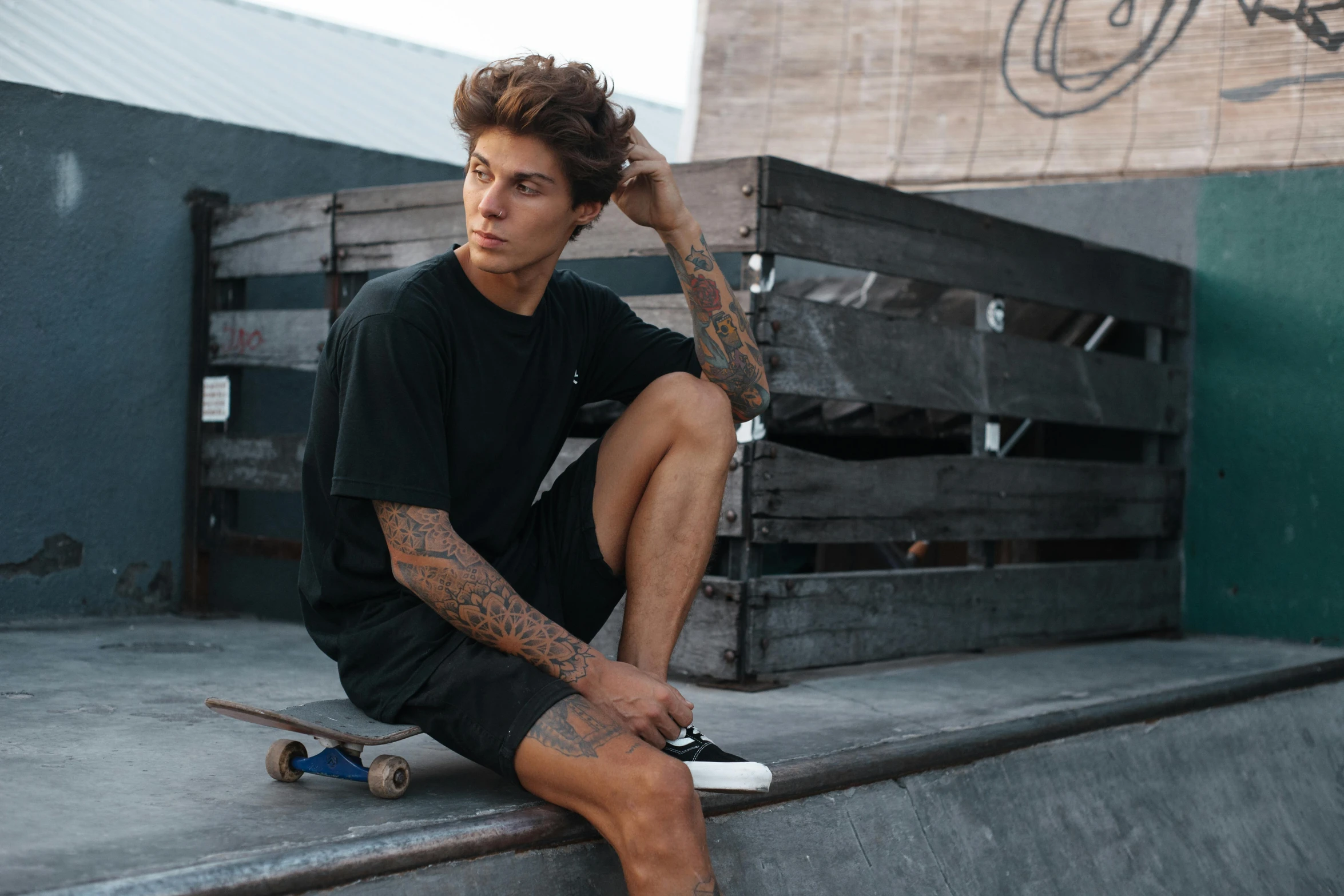 a man sitting on the edge of a ramp with his skateboard