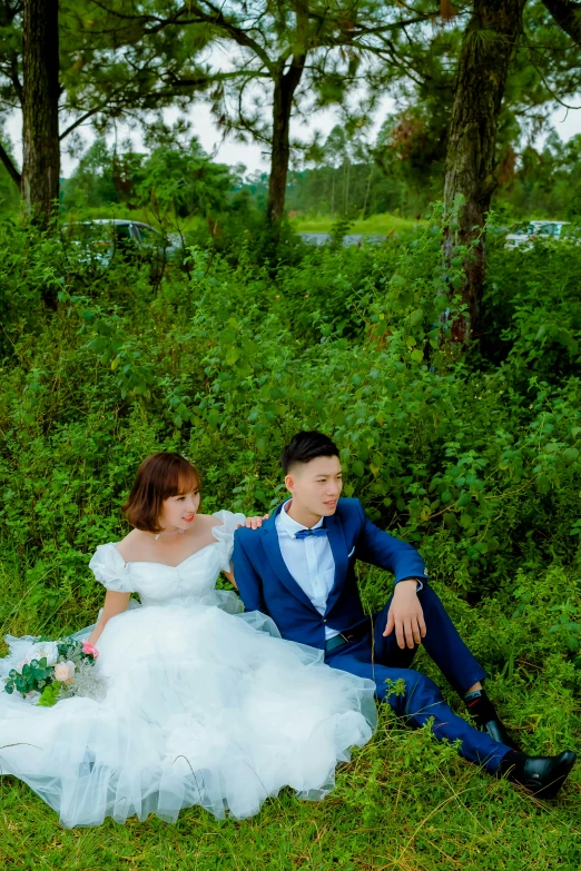 a man and woman are sitting in the grass