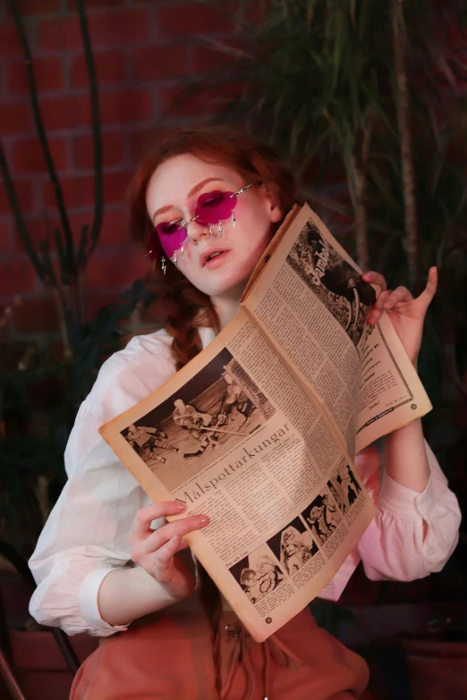 a woman in white shirt and pink sunglasses holding an old fashioned newsprint