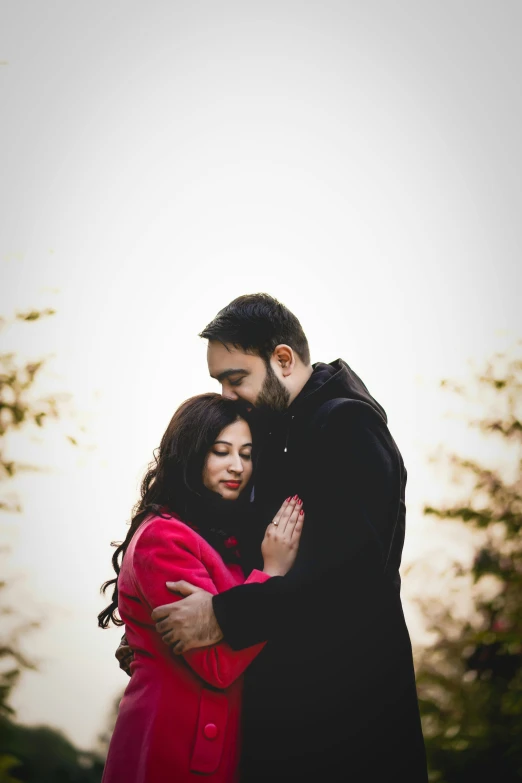 a woman and man standing in front of trees