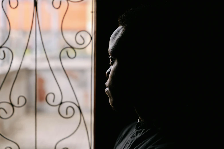 the back side of a person next to a window with swirly glass panels