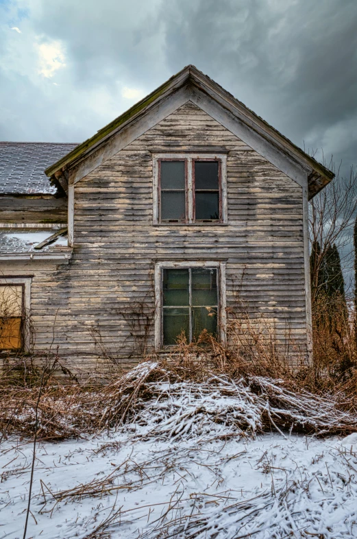 an old weathered wood house is partially boarded up