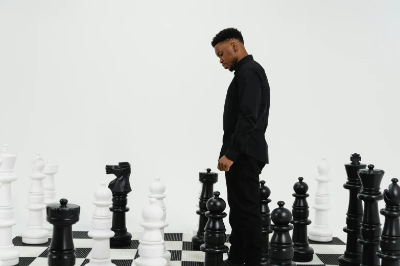 a man standing next to a black and white chess board