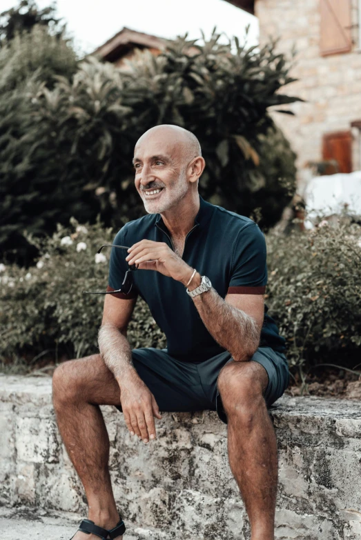 a man sitting on a ledge wearing shorts