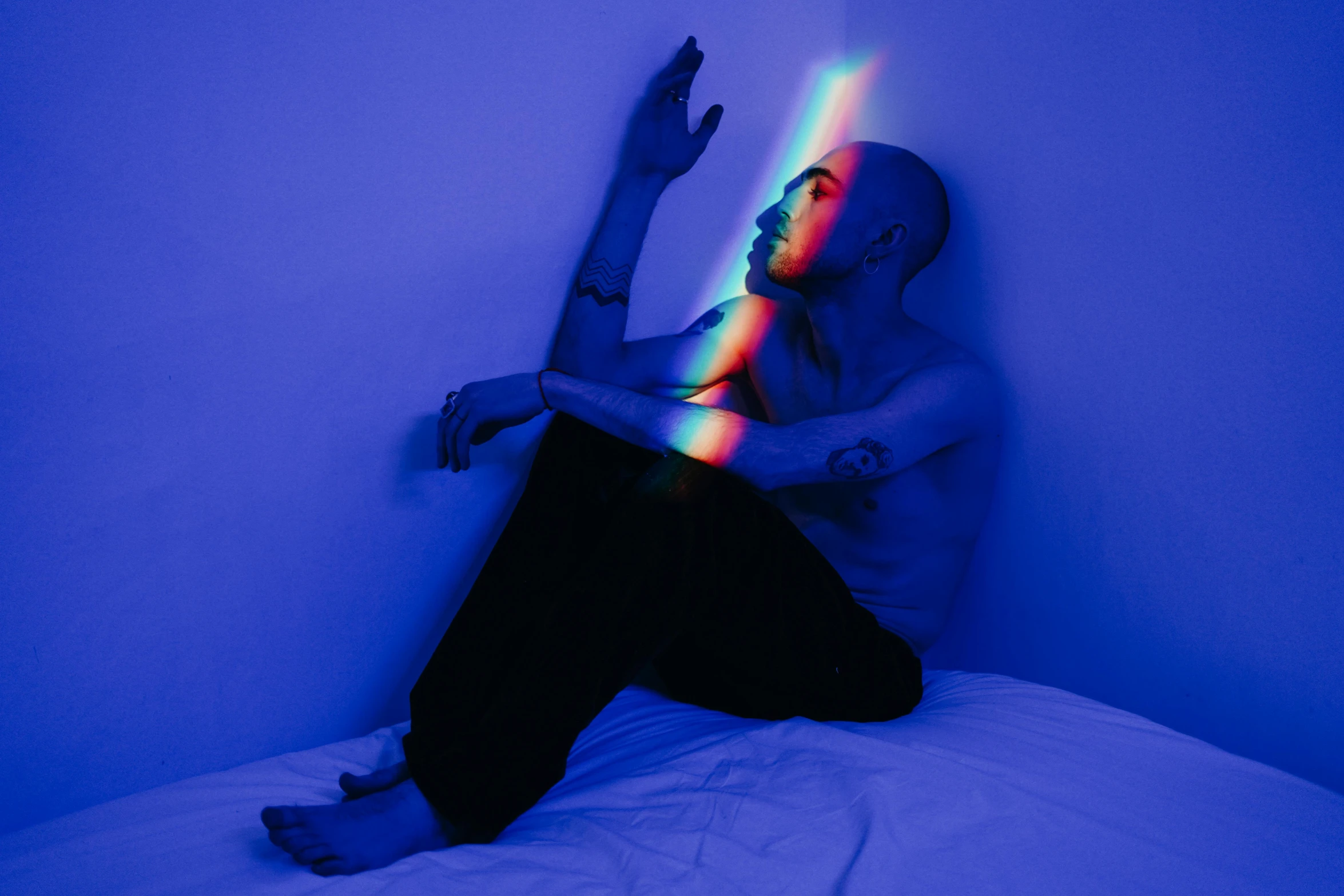 a man is sitting on a bed and has colored lights in his hair