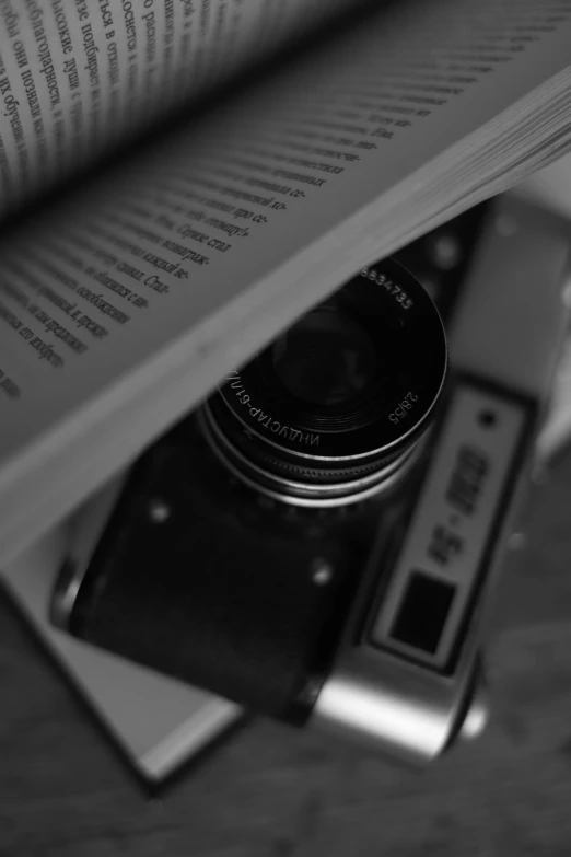 an open book on the floor shows a camera resting atop an open book