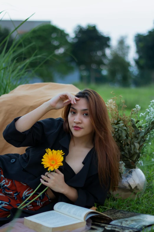 a beautiful young woman laying on the ground with a flower