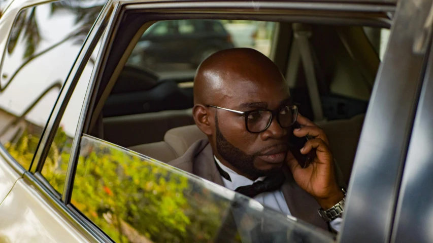 a man sitting in the driver seat of a car and talking on a cell phone