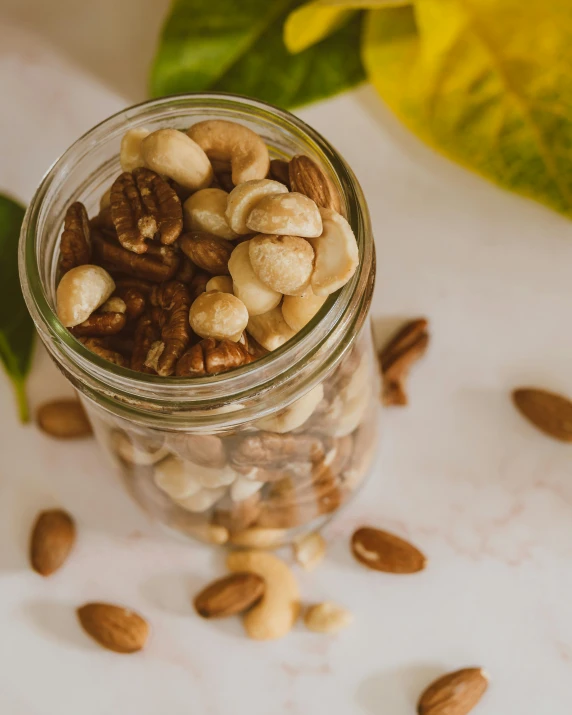 several nuts in a glass jar on a white table