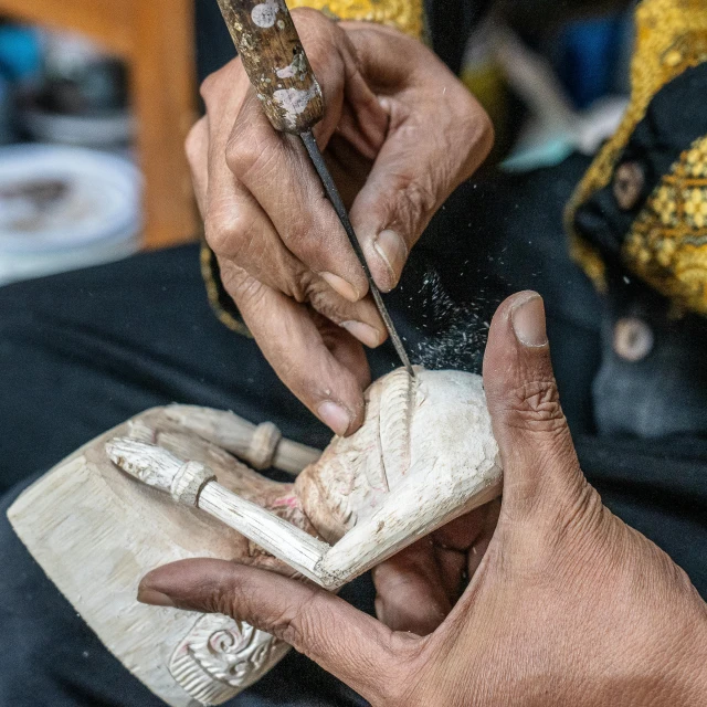 someone is shaving a small object of pottery