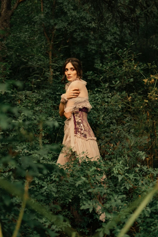 a woman in a dress walks through trees