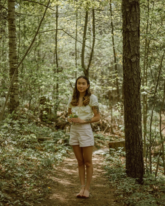 a woman standing in the woods with a frisbee