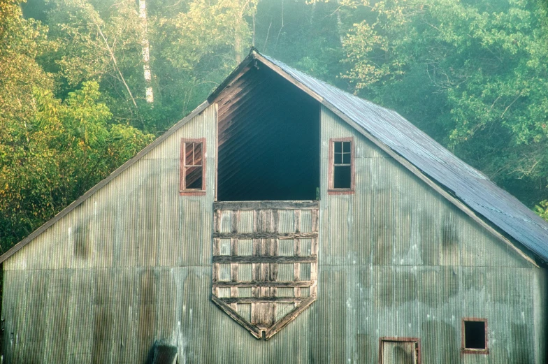 a metal barn sits next to a forest