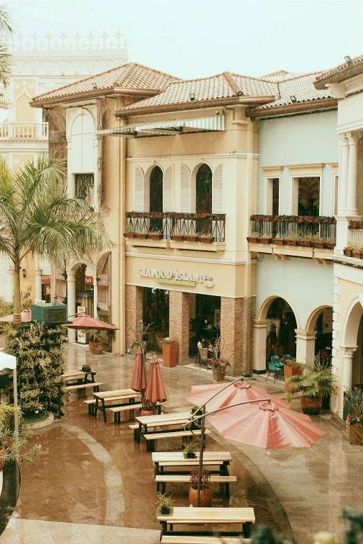 the view of a large courtyard with several tables and umbrellas