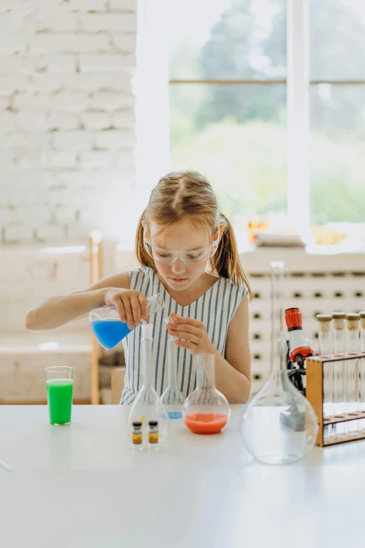 little girl in a striped dress preparing a science experiment