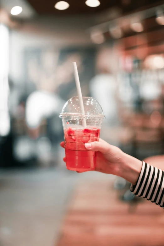 a hand holding a drink with a straw in it