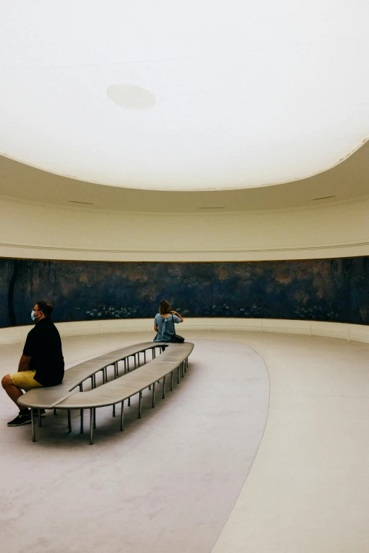two people sitting on benches in a circular room