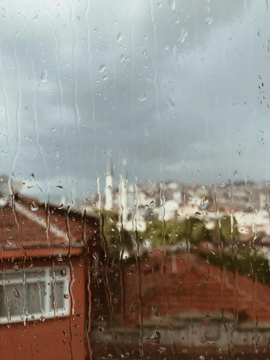 a rain covered window with a cityscape in the background