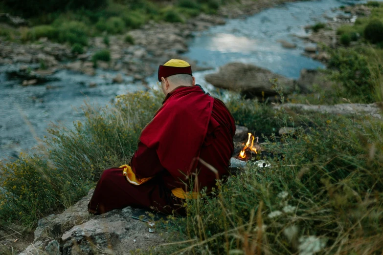 a monk meditating on a rock in a stream