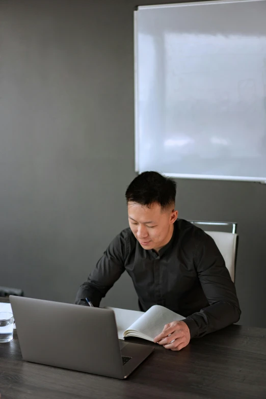 a young asian man working at a desk with his laptop