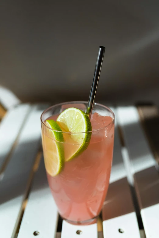 a close up of a cocktail with lime and a drink straw