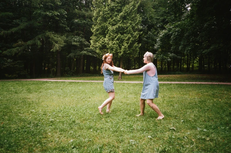 two woman dancing in the grass holding hands