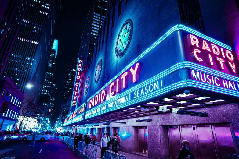 people standing outside an arena sign at night