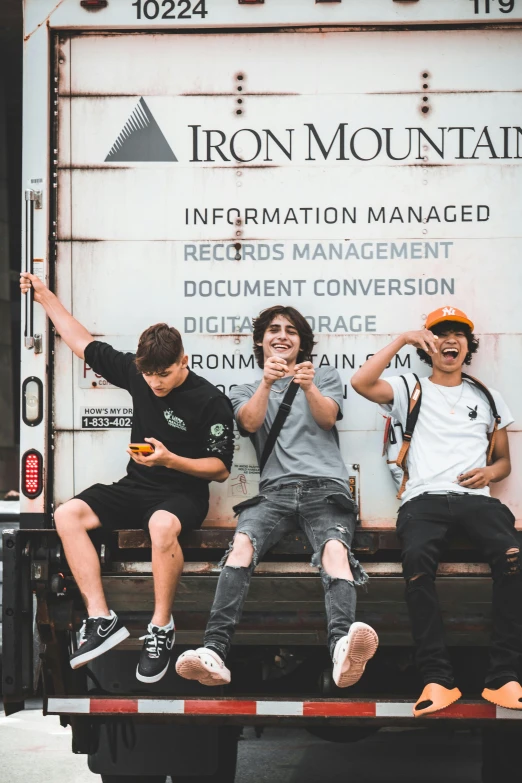 four men sitting on a bed of a truck