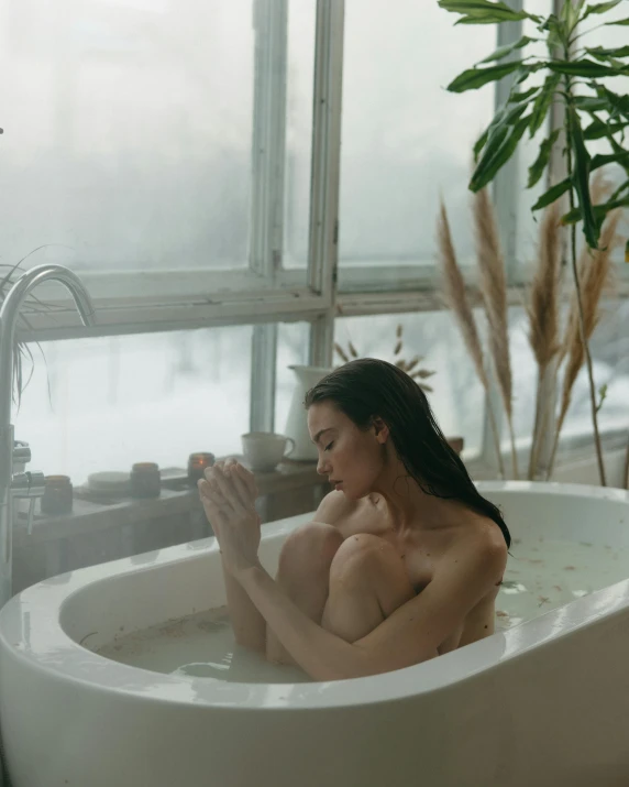 a woman sits in a white bath tub with water flowing around her