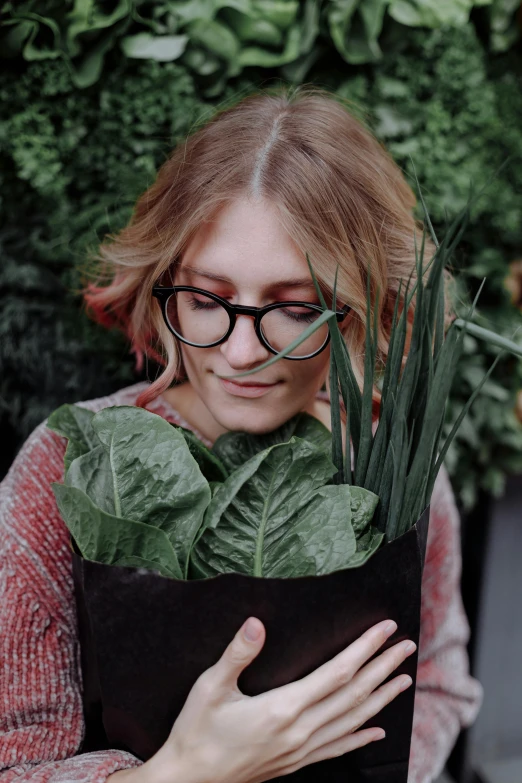 a woman holding a plant in front of her face