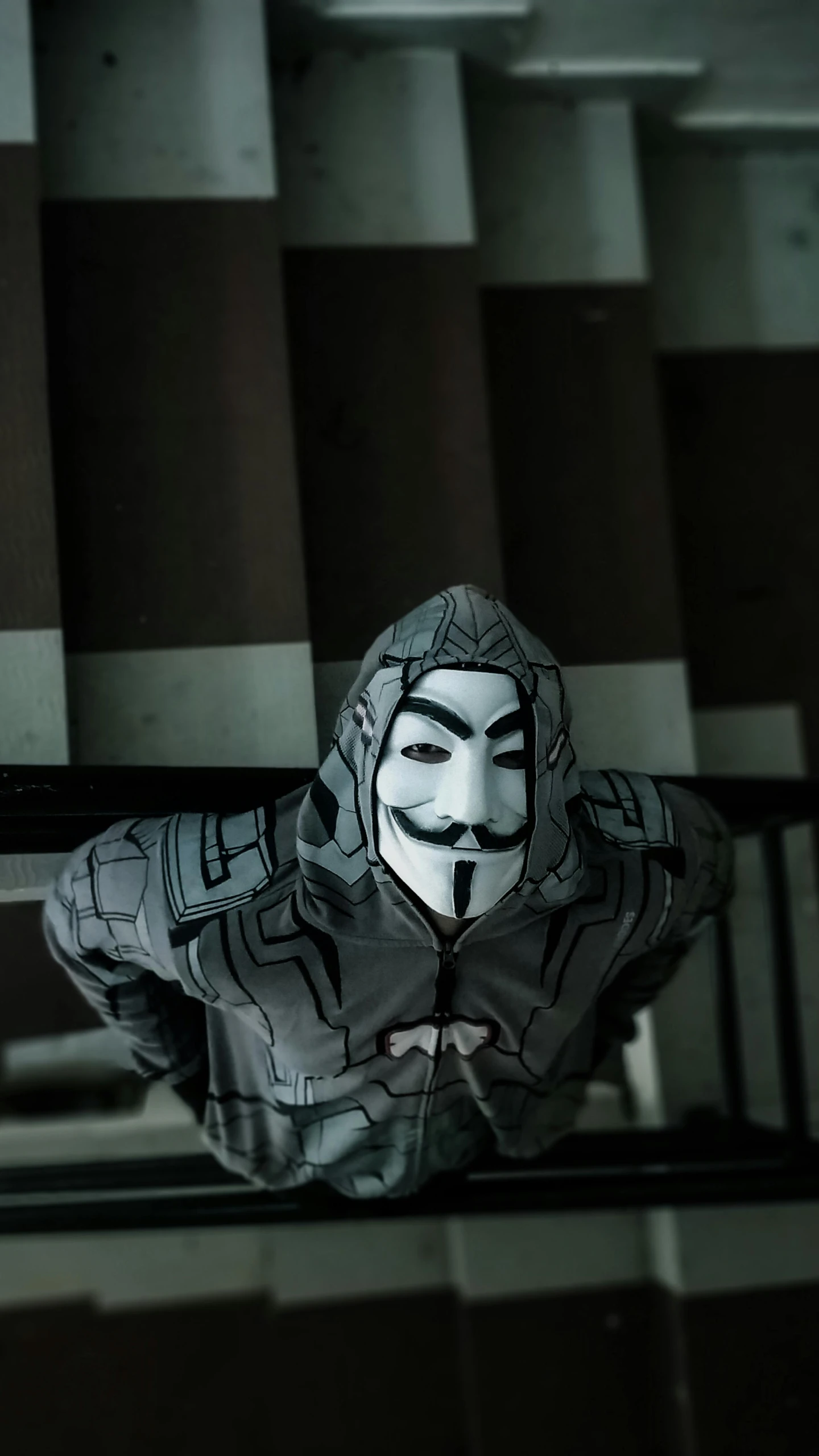 a masked person wearing a hoodie posing with his hands to his face