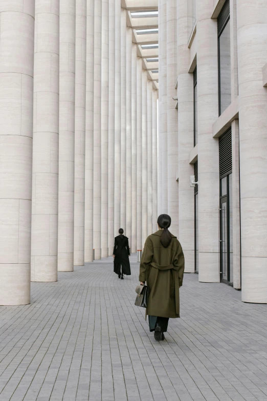 two people walking down a sidewalk in an enclosed space