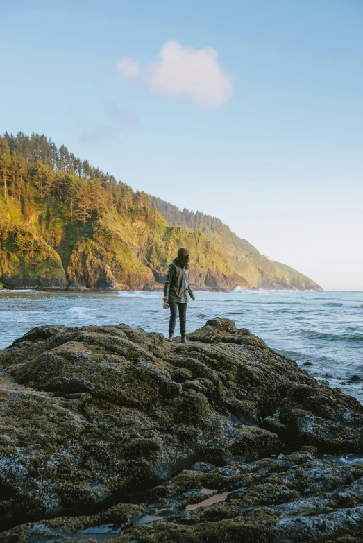 the person is standing on the rocks in front of the water