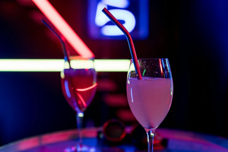 a pink liquid and an orange drink in glasses