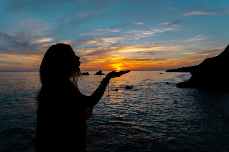 a woman is standing by the ocean holding soing