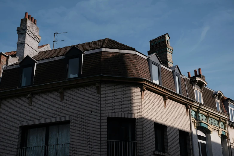 a brick house with windows and chimneys in front of a blue sky