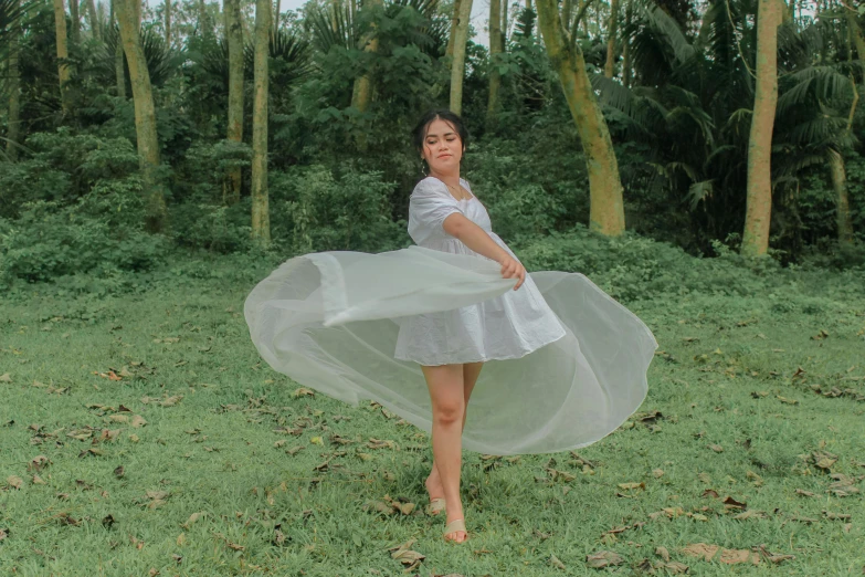 the woman is posing on the grass with a white dress