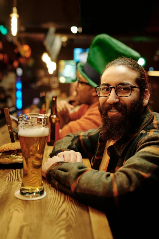 there is a man that is sitting at a table with a beer